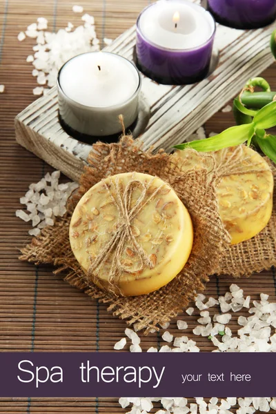 Hand-made soap and sea salt on grey bamboo mat — Stock Photo, Image