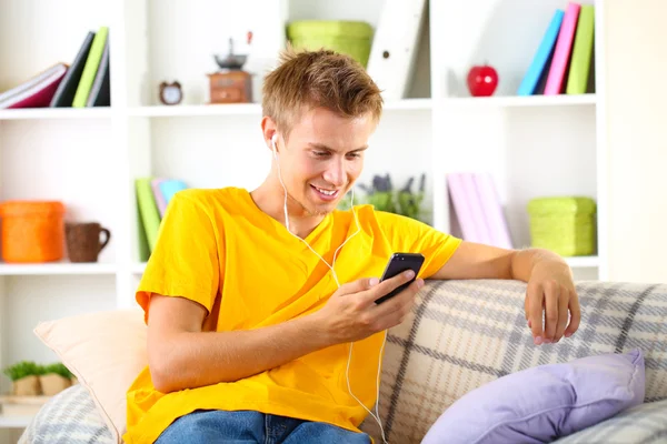 Ung man koppla av på soffan med mobiltelefon — Stockfoto