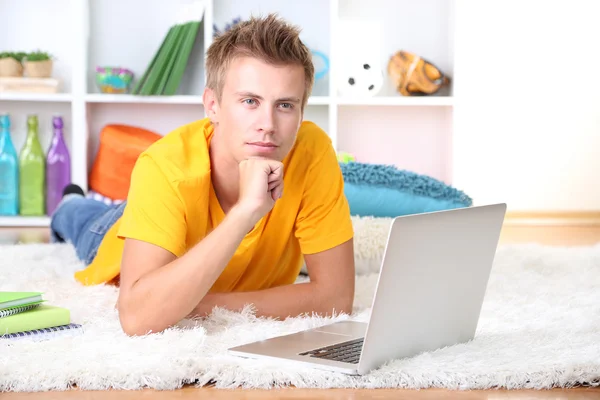 Junger Mann entspannt mit Laptop auf Teppich — Stockfoto