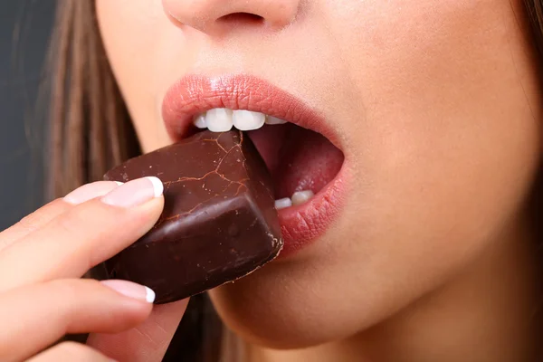 Closeup of woman eating chocolate candy — Stock Photo, Image