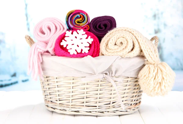 Warm knitted scarves in basket on winter background — Stock Photo, Image