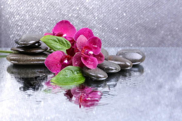 Güzel çiçek açan orkide su damlaları ve açık renk arka plan üzerinde spa taşlar ile kompozisyon — Stok fotoğraf