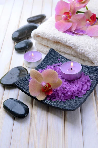 Zátiší s krásnou kvetoucí orchidej květina, ručník a mísa s mořskou solí, na barevné dřevěné pozadí — Stock fotografie