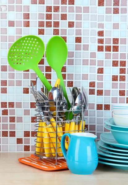Geschirr und Besteck in der Küche auf dem Tisch auf Mosaikfliesen Hintergrund — Stockfoto