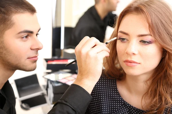 Mladý kluk kadeřník dělá make-up krásná žena v salonu krásy — Stock fotografie