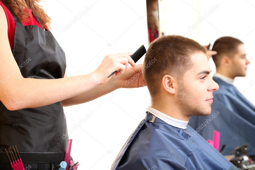 Beautiful girl hairdresser cut guy in beauty salon