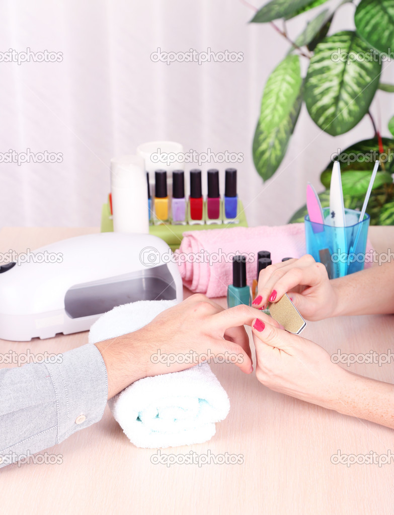 Girl manicurist doing manicure for man in beauty salon