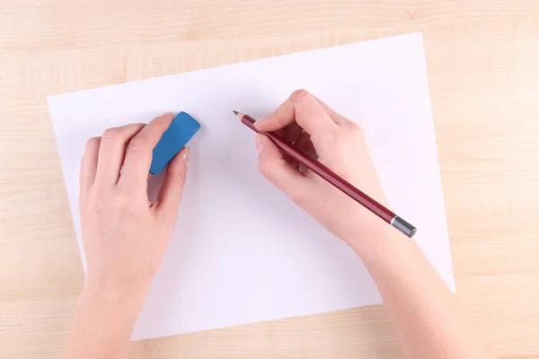 Händer anläggning penna och radera med papper på trä bakgrund — Stockfoto