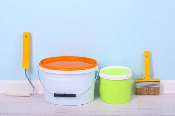 Paints, roll and paintbrush on floor in room on wall background — Stock Photo, Image