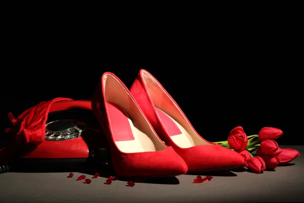 Szép piros női cipő és retro telefon, fekete háttér — Stock Fotó