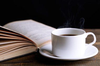 sıcak kahve ile masaya koyu arka plan üzerinde kitap