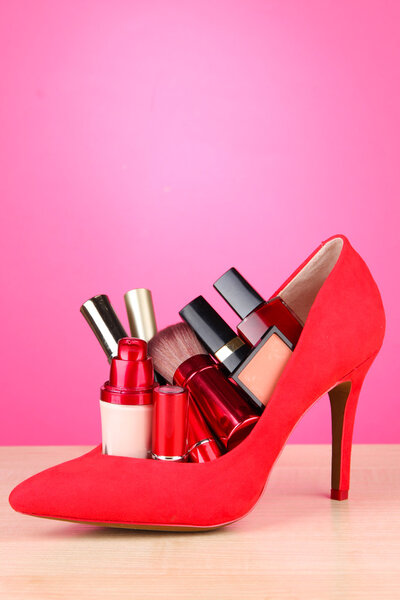 Beautiful red female shoe with cosmetics, on pink background