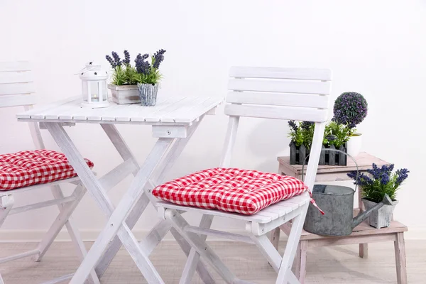 Cadeiras de jardim e mesa com flores em suporte de madeira sobre fundo branco — Fotografia de Stock