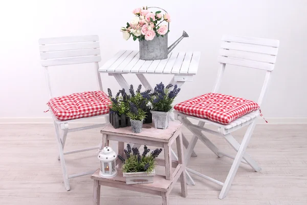 Cadeiras de jardim e mesa com flores em suporte de madeira sobre fundo branco — Fotografia de Stock