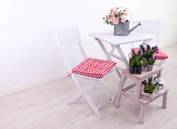 Cadeiras de jardim e mesa com flores em suporte de madeira sobre fundo branco — Fotografia de Stock