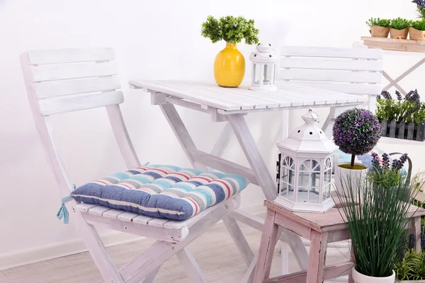 Садові стільці та стіл з квітами на дерев'яних підставках на білому тлі — стокове фото