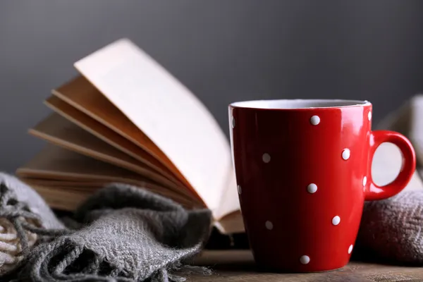 Чашка горячего чая с книгой и клеткой на столе на сером фоне — стоковое фото