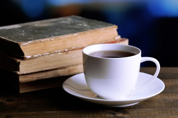 Beker van hete thee met boeken op tafel op lichte achtergrond — Stockfoto