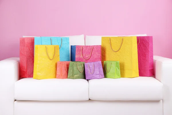 Sacos de compras coloridos no sofá, no fundo da parede de cor — Fotografia de Stock
