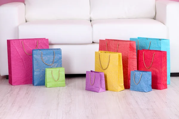 Colorful shopping bags on sofa, on color wall background — Stock Photo, Image