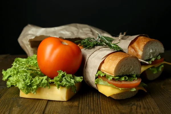 Świeża i smaczna kanapka na drewnianym stole na czarnym tle — Zdjęcie stockowe