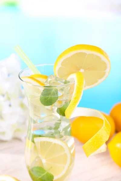 레몬과 밝은 파란색 배경에 테이블에 민트와 함께 칵테일의 유리 — 스톡 사진