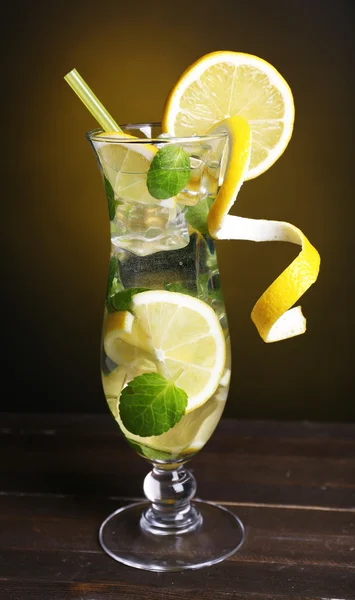 Glass 的鸡尾酒与柠檬和薄荷上暗黄色背景表格 — 图库照片