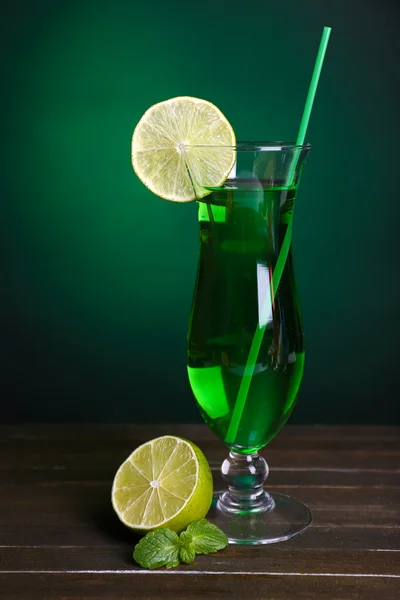 Glass of cocktail on table on dark green background — Stock Photo, Image