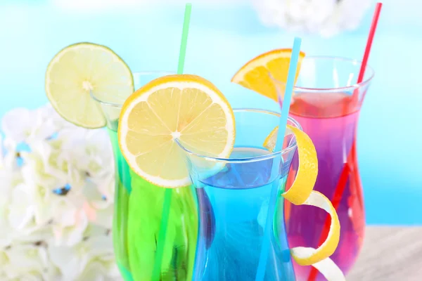 Glasses of cocktails on table on light blue background — Stock Photo, Image