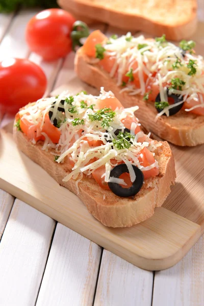 Delicious bruschetta with tomatoes on cutting board close-up — Stock Photo, Image