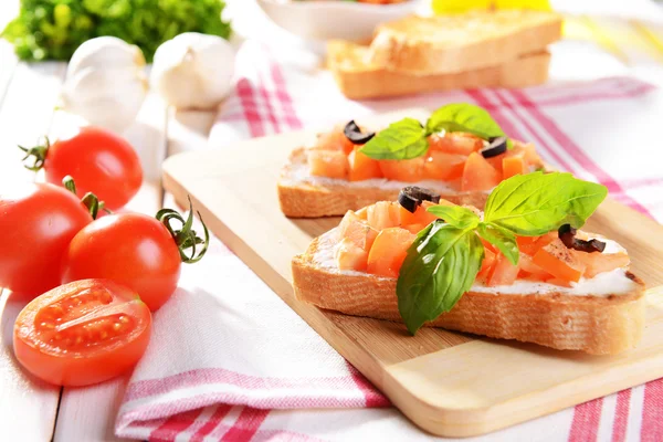 Deliciosa bruschetta con tomates en la tabla de cortar de cerca —  Fotos de Stock