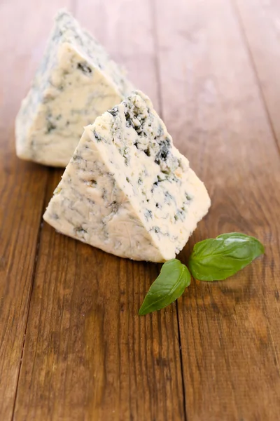 Smakelijke blauwe kaas met basilicum, op houten tafel — Stockfoto