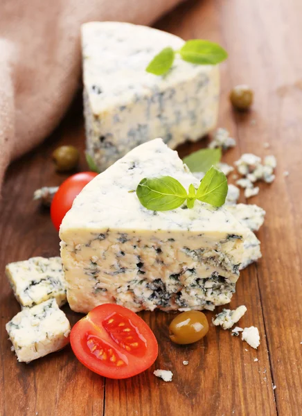 Вкусный голубой сыр с помидорами, оливками и базиликом, на деревянном столе — стоковое фото