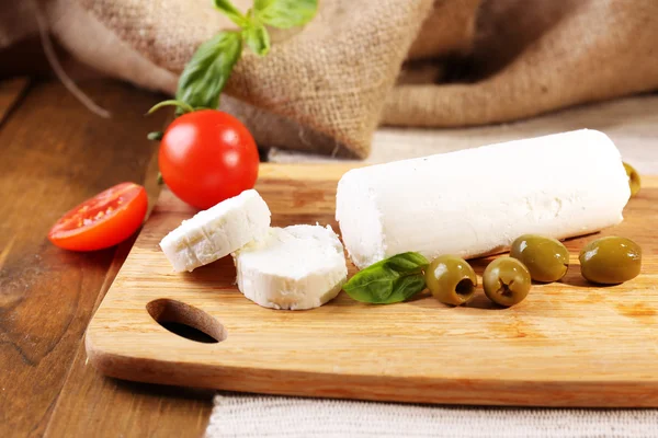 Queijo saboroso com tomate, azeitonas e manjericão, sobre tábua de corte — Fotografia de Stock