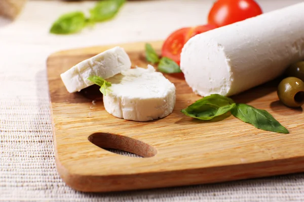 Queijo saboroso com tomate, azeitonas e manjericão, sobre tábua de corte — Fotografia de Stock