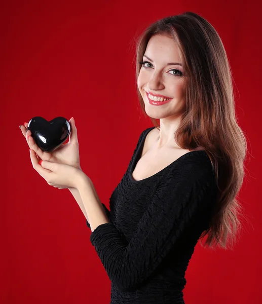 Atraktivní žena se srdcem na červeném pozadí — Stock fotografie