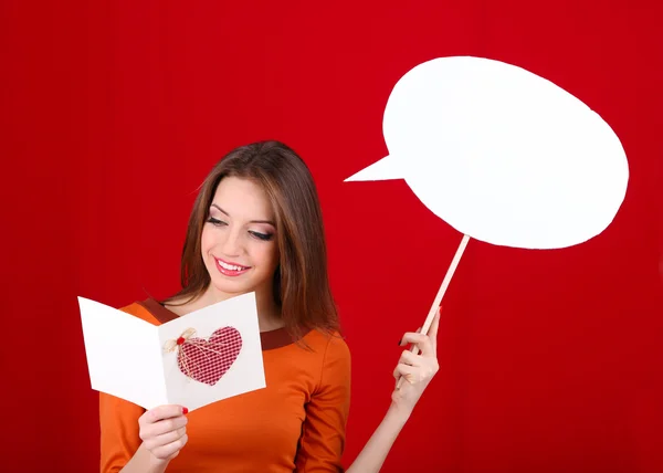 Mujer atractiva con postal, sobre fondo rojo — Foto de Stock