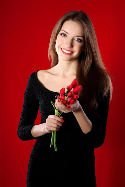 Attraktive Frau mit Blumen auf farbigem Hintergrund — Stockfoto