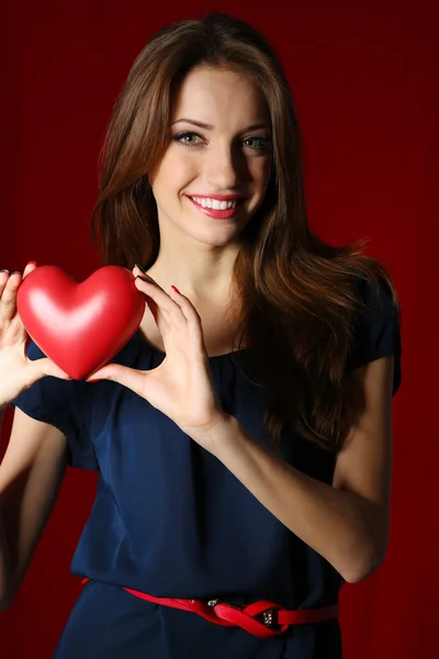 Attractive woman with heart, on red background — Stock Photo, Image