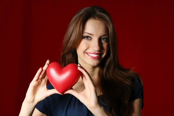 Mujer atractiva con corazón, sobre fondo rojo — Foto de Stock