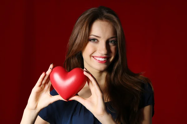 Aantrekkelijke vrouw met hart, op rode achtergrond — Stockfoto