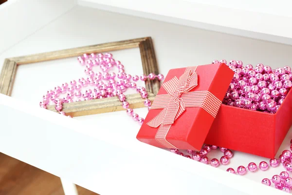 Подарочная коробка и бусины в открытом ящике стола закрыть — стоковое фото