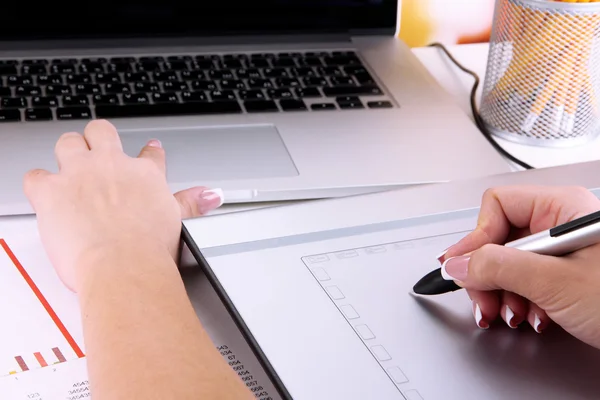 Женская рука с помощью графического планшета на столе крупным планом — стоковое фото
