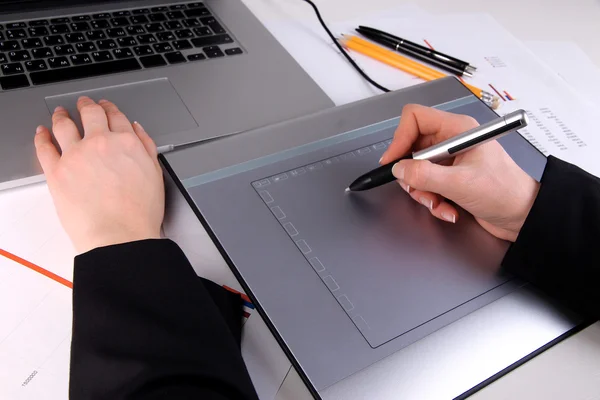 Женская рука с помощью графического планшета на столе крупным планом — стоковое фото
