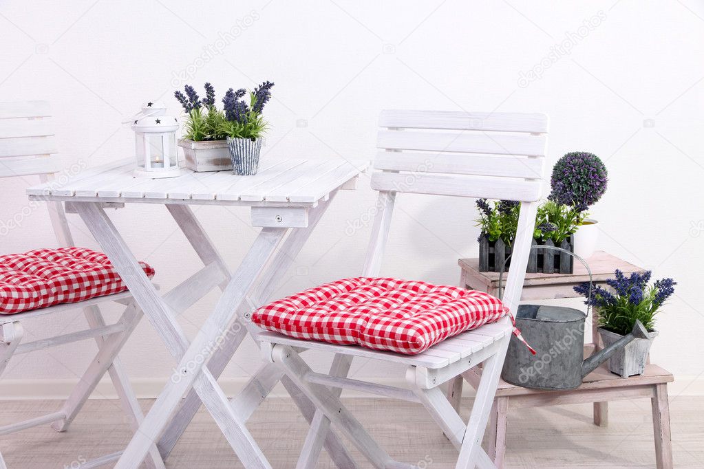 Garden chairs and table with flowers on wooden stand on white background