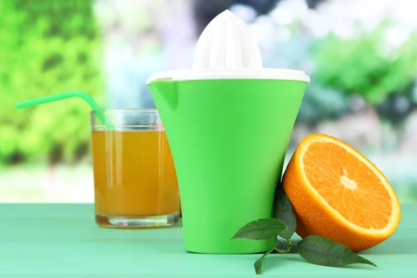 Citruspress, glas juice och mogen orange på gröna träbord — Stockfoto