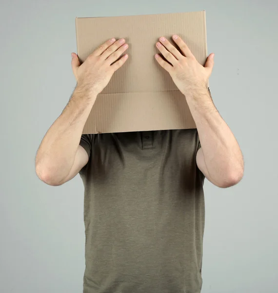 Man met kartonnen doos op zijn hoofd op grijze achtergrond — Stockfoto