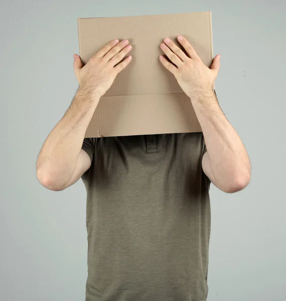 Man with cardboard box on his head on grey background — Stock Photo, Image