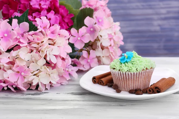 Sabroso cupcake con crema de mantequilla, en plato, sobre fondo de madera de color — Foto de Stock