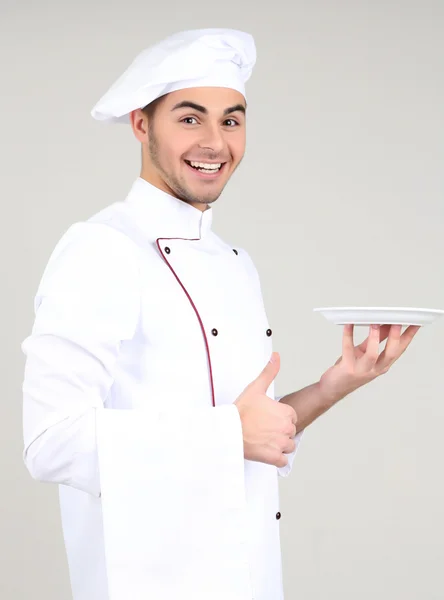 Профессиональный повар в белой форме и шляпе, на сером фоне — стоковое фото